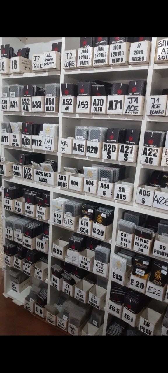 Estante del taller con repuestos de baterías ordenados por modelo de celular