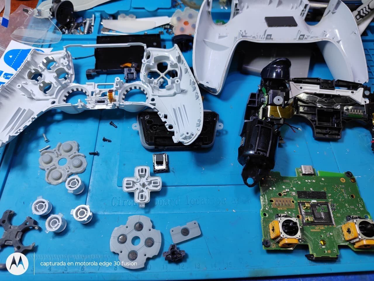 Mando de PS5 desarmado con gomas, botones y placa sobre la mesa